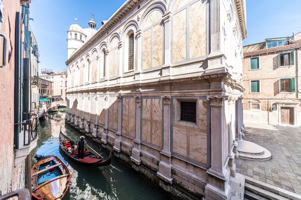 Gondolas passing the marble flank of Santa Maria dei Miracoli